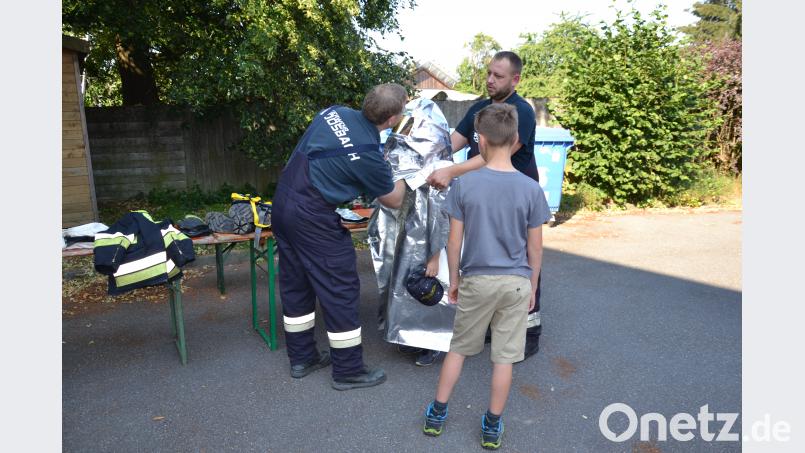 Die Grundschüler schlüpfen in die Schutzkleidung der Feuerwehr Moosbach. gi