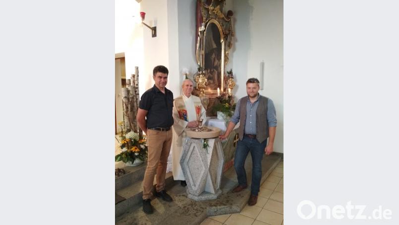 Theo Bauer (rechts) mit seinem Meisterwerk. Über den Taufstein in der Filialkirche Tröbes freuen sich Pfarrer Josef Most (Mitte) und Kirchenpfleger Bernhard Rom. gi