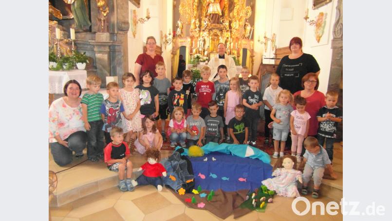 Die Kindergartenkinder vor dem Volksaltar und die symbolisch dargestellte Schöpfungsgeschichte mit Pfarrer Stretz, dem Kindergartenpersonal sowie Leiterin Kerstin Dilling (zweite Reihe, Zweite von rechts). hl