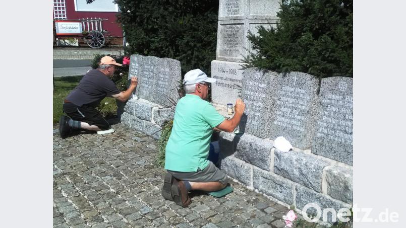 In der prallen Sonne ziehen Reinhard Bauer (rechts) und Bernhard Roth die Schrift am Ehrenmal nach.. ld