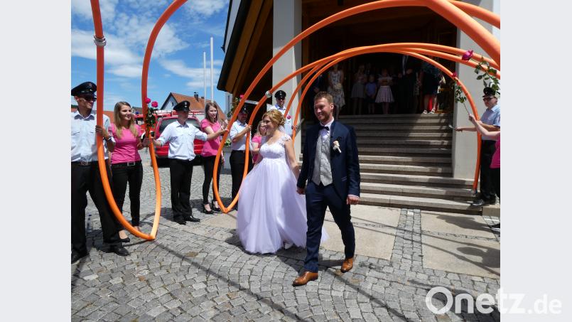 Gleich am Kirchenportal wird das Brautpaar unter einem Bogen aus Feuerwehrschläuchen empfangen. wlr