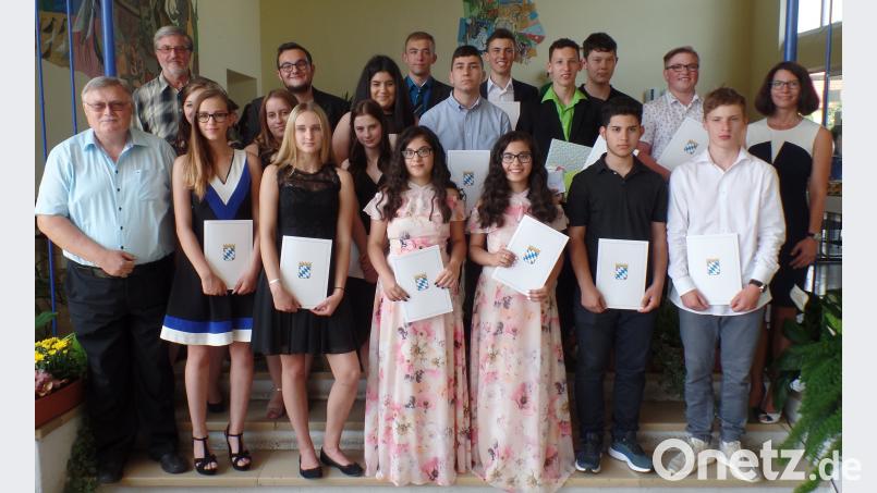 Nick Müller, Kevin Jandl und (Sechster und Fünfter von rechts) sowie Sophia Wolf (vorne, Dritte von links) sind die Klassenbesten der Speichersdorfer Mittelschule. Bürgermeister Manfred Porsch und Schulleiter Werner Leupold (von links) sowie Klassenlehrerin Marion Vogel (rechts) übergeben den 17 Schulabgängern die Zeugnisse. Brendel, Hubert (BR)