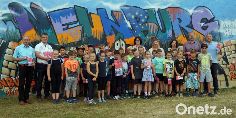 Genauso bunt, wie die Graffitiwand am Schulgebäude, sind auch die Veranstaltungen im Ferienprogramm. Die neue Auflage präsentierten die Bürgermeister Albert Krieger (Bodenwöhr) und Martin Birner (Neunburg, von links) sowie Jugendbeauftragter Harald Klatzka, ArGe-Jugend-Vorsitzender Georg Keil, Schulleiterin Sabine Bauer und die Verwaltungsmitarbeiterinnen Martina Greiner und Elisabeth Lottner (von rechts), zusammen mit mehreren Kindern. agr