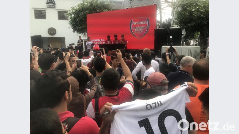 Bei einer Autogrammstunde des FC Arsenal in Singapur zeigt ein Fan ein Nationaltrikot von Mesut Özil (auf dem Podium, rechts). Zu seinem Rücktritt und seinen Vorwürfen sagte er nichts. Christoph Sator/dpa