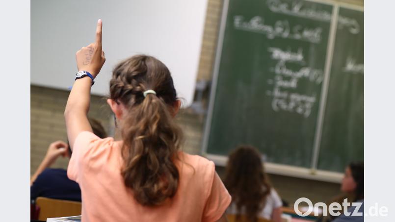 Eine Schülerin hebt im Unterricht den Finger. Daniel Karmann/dpa