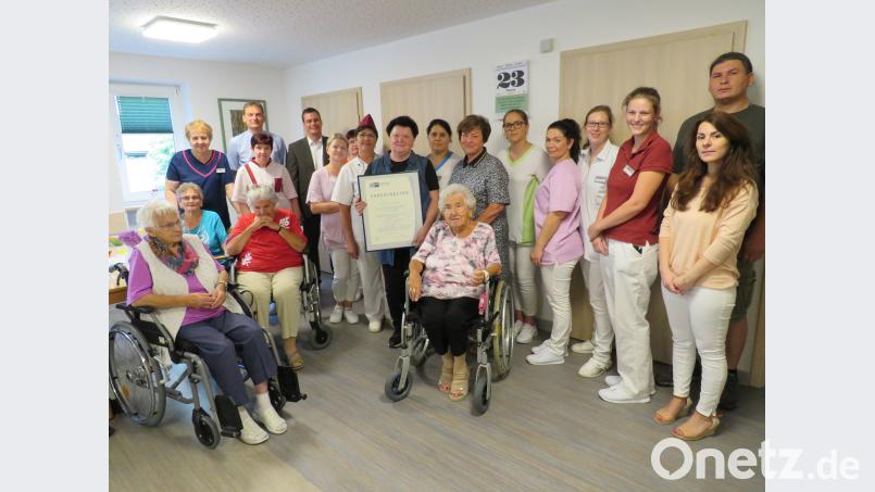 Im Kreise der Bewohner und ihrer Kollegen wird sie ausgezeichnet: Hildegard Krischkowsky bekommt von Florian Rieder, Bürgermeister Ernst Schicketanz (hinten, von rechts) und Irina Löffler-Ilinov (Siebte von rechts) die Urkunde. adj