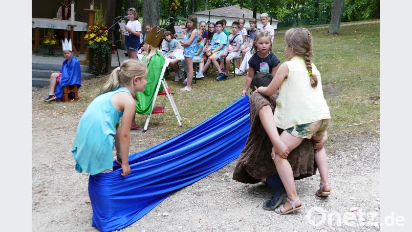 Kinder aus dem Hort St. Anna zeigen in einem Spiel, wie Christopherus Reisende über einen Fluss trägt. wbe