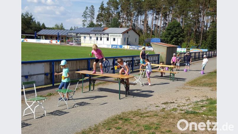 Die Kinder beim Spiel Wasserlauf: Die Mannschaft, die am meisten Wasser in ihren Eimer leeren kann, ist Sieger. exb