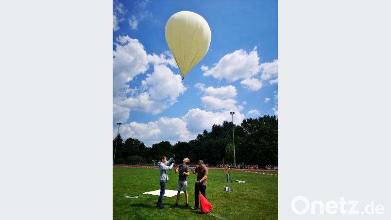 Vor einigen Zuschauern lassen zwei Schüler der "Technik- und Schraubgruppe" und Physiklehrer Patrick Lichtinger (rechts) den Wetterballon nach oben. exb