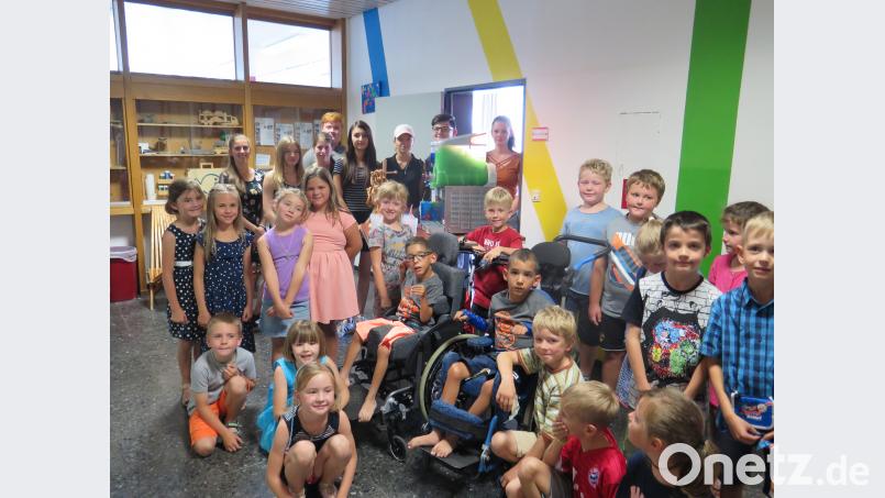 Die Klasse 1 a freut sich mit den Zwillingen Malik und Damian Nelson (Mitte) sowie den Organisatoren der Benefiz-Veranstaltung über die gelungene Aktion mit der Slush-Eis-Maschine. jzk