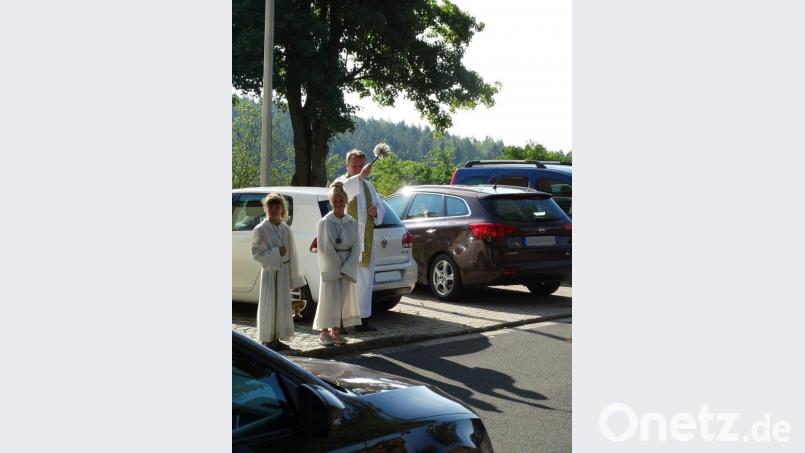 Mit Weihwasser besprengt Pfarrer Josef Waleszczuk bei der Fahrzeugsegnung die vor der Kirche abgestellten Autos. luk