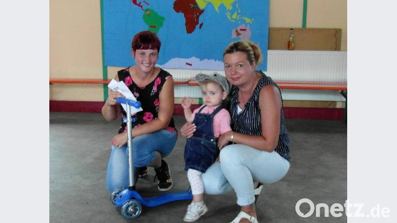 Elternbeiratsvorsitzender Stephanie Lukas (links). übergibt den Roller an Gewinnerin Emelie Janner und ihre Mutter. hl