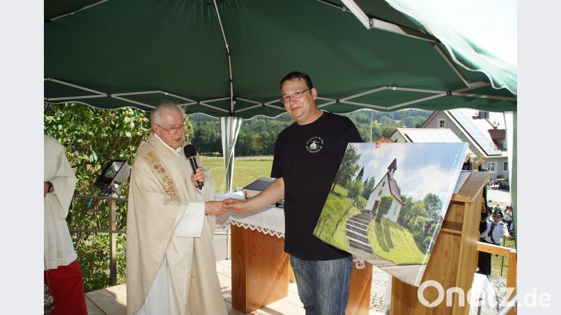 Michael Ulschmid, Vorsitzender des Heimatvereins St. Anna Waier - Schwarzach, überreichte BGR Pfarrer Michael Reitinger ein Bild der Wallfahrtskapelle. mmj