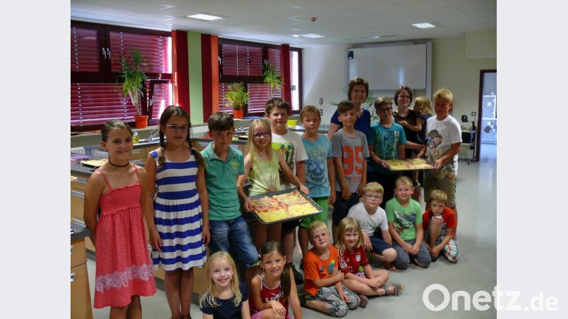 Bevor die Bleche in den vortemperierten Ofen geschoben wurden, präsentierten die kleinen Pizzabäcker ihre Kreation. Im Bild mit Leiterin Gabi Kohl und Tochter Susanne mit Töchterchen Hanna auf dem Arm. kgg