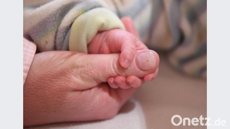 Ein neun Tage alter Junge hält den Daumen einer Hebamme. Uli Deck/dpa