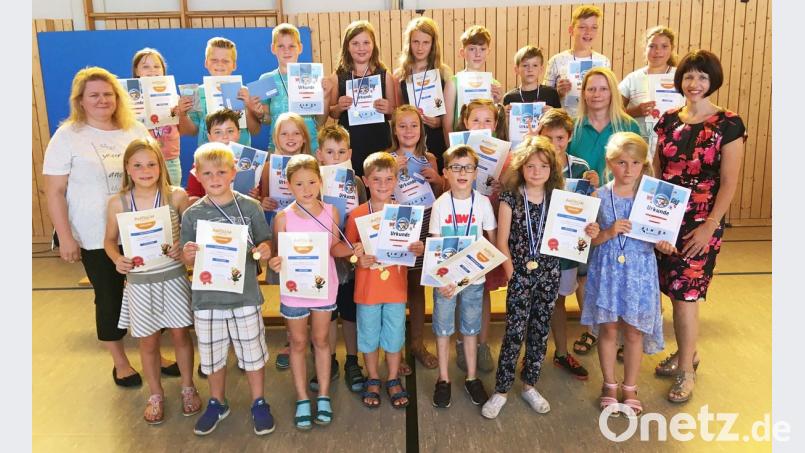 Stolz halten die Kinder ihre Urkunden in Richtung Kamera. ü
