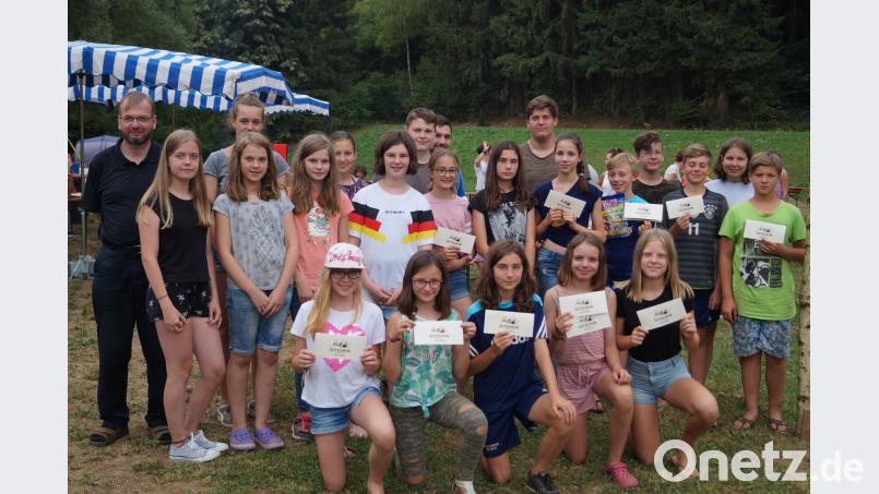 Süße Freude im Zeltlager: Pfarrer Thomas Stohldreier (links) verteilte an die Sieger des Wettbewerbs "Boote bauen" und der Lagerolympiade Eisgutscheine und Süßigkeiten. du