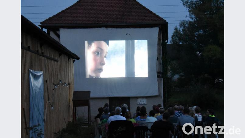 Auf einer Theaterleinwand an der Alten Schießstätte läuft „Ein Sack voll Murmeln“, während sich im Hintergrund die Waldnaab durch die Kreisstadt windet. bgm