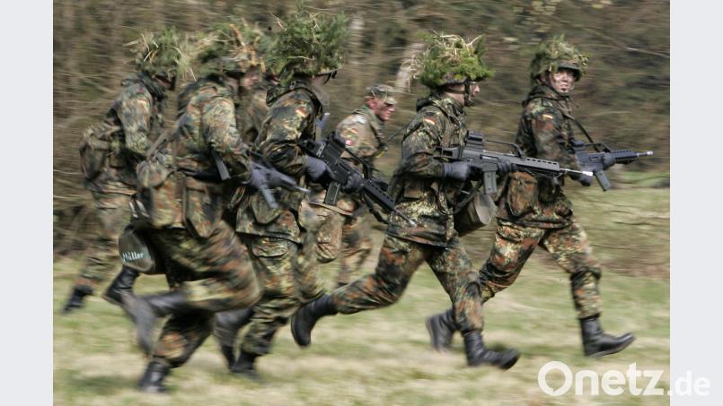 Mit Blattwerk und Gras getarnte Wehrpflichtige. Frank May/dpa