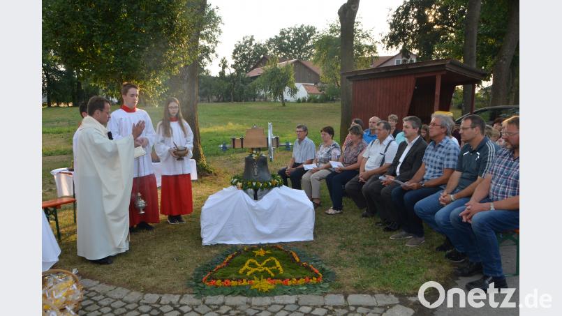 Sommerlich geschmückt präsentiert sich die neue Glocke zur Weihe vor dem Dorfkreuz in Unterlind. Dekan Alexander Hösl spricht das Segensgebet. Unterlind bekommt mit einer "Regina coeli" ein Juwel für den Glockenturm. dob