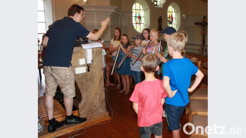 Organist Florian Löw (links) erklärt den 18 Kindern beim Ferienprogramm, wie die Orgel funktioniert. Dann dürfen die Mädchen und Buben auch durch die Pfeifen pusten und testen, welche Töne dabei herauskommen. lk
