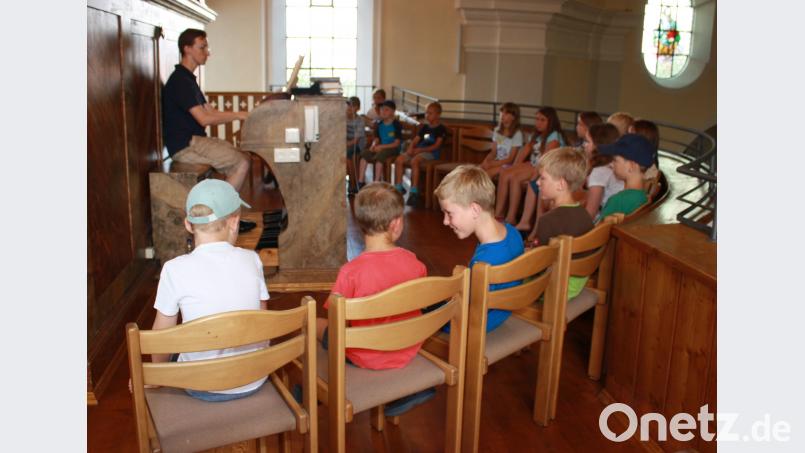 Organist Florian Löw (links) erklärt den 18 Kindern beim Ferienprogramm, wie die Orgel funktioniert. lk