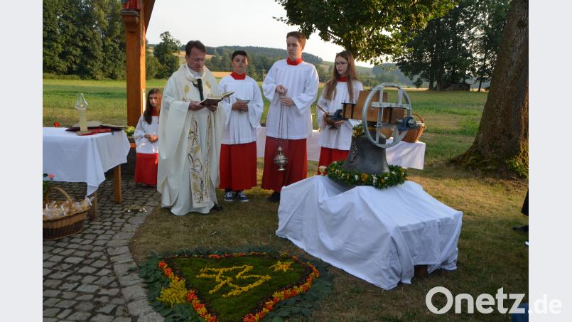 Sommerlich geschmückt präsentiert sich die neue Glocke zur Weihe vor dem Dorfkreuz in Unterlind. Dekan Alexander Hösl spricht das Segensgebet. Unterlind bekommt mit einer "Regina coeli" ein Juwel für den Glockenturm. dob