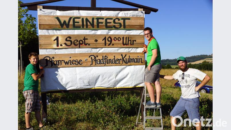 Manuel Schraml, David Maschauer und Jonnathan Scharf führen das Organisationsteam an. Sie weisen mit einer Tafel am Ortseingang auf das Weinfest hin. bkr