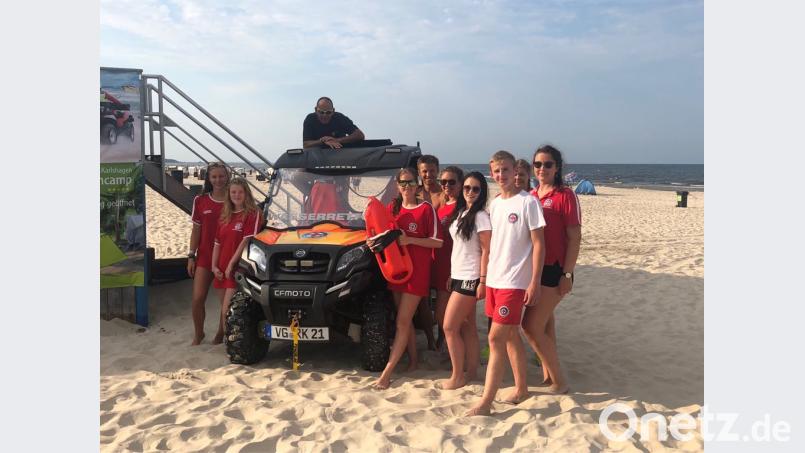 Marlena Münchmeier und Daniel Hirschmann (vorne, Zweite und Dritter von rechts) zusammen mit weiteren Rettungsschwimmern an der Ostseeküste vor dem speziellen Strandfahrzeug, exb