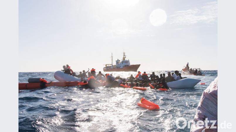 Zahlreiche Flüchtlinge, die auf Booten von Libyen aus nach Italien übersetzen wollten, werden während eines Rettungseinsatzes vor der libyschen Küste geborgen. Im Hintergrund das Rettungsschiff Aquarius. Laurin Schmid/SOS Méditerranée/dpa