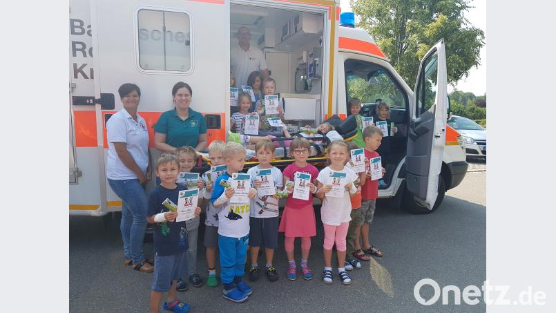 Die 17 Vorschulkinder des Kinderhauses Pechbrunn nach ihrem Trau-Dich-Kurs mit Manuela Lang (links), Natalie Wölfl (Zweite von links) und Robert Hoyer (im Rettungswagen) vom BRK Mitterteich. exb