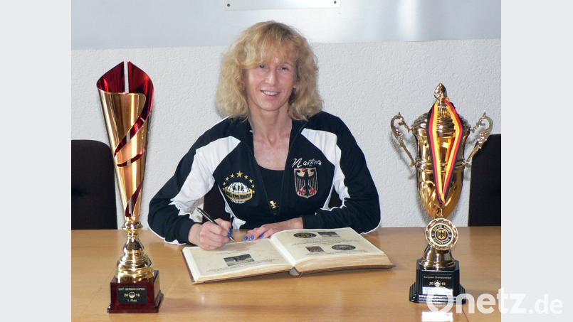Ihre Pokale bringt sie mit: Martina Whitten, Deutsche Meisterin in der Kategorie „Damen Figure Masters“, verewigt sich im Goldenen Buch der Marktgemeinde. Links im Bild steht der Pokal für den Sieg bei den WFF German Open, rechts der für Rang sechs bei der European Championship. lep