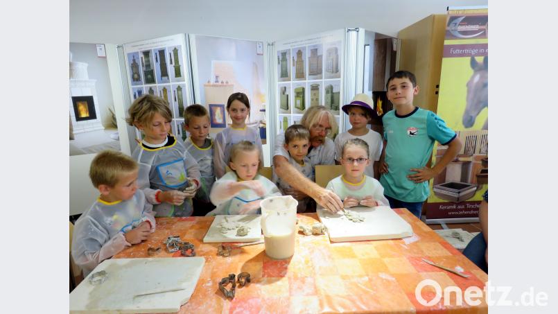 Josef Regner (Vierter von links) zeigt den Kindern, wie der Ton geknetet werden muss. ubb