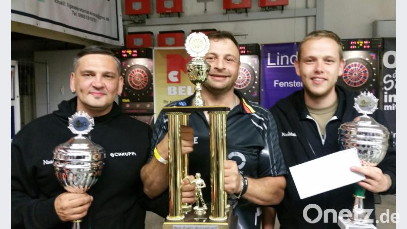 Der zweite Dartchef und Gönner Thomas Bösl (Mitte) überreicht an die Gewinner des Teamturniers Dave Haberberger und Mike Winkler (li) die Pokale und den Siegercup. gz