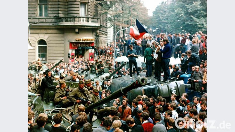 Demonstranten umringen in der Innenstadt von Prag sowjetische Panzer und stehen mit einer Fahne der Tschechoslowakei auf einem umgekippten Militärfahrzeug. Libor Hajsky/dpa