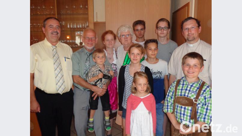 Das goldene Jubelpaar Hans und Hannelore Kredler (Mitte), eingerahmt von den acht Enkelkindern und Bürgermeister Peter Dotzler (links) sowie Pfarrvikar Christian Preitschaft (rechts). dpe