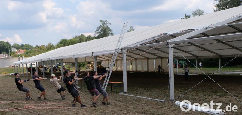 Mit vereinten Kräften ziehen die Burschen das Zeltdach über das Stahlskelett. le