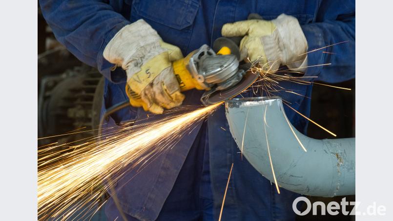Ein Arbeiter schleift mit einem Trennschneider an einem Rohr in einer Rohölverarbeitungsanlage. Arbeitnehmer im Osten arbeiten weiter länger als im Westen.  Patrick Pleul/dpa-Zentralbild/dpa
