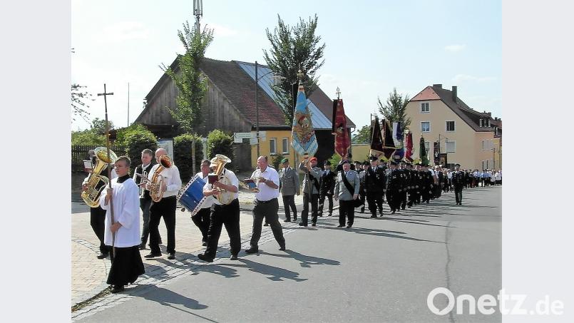 Ein langer Zug ist zum Friedhof unterwegs, angeführt von der Blaskapelle und den Vereinen. Bild: hl