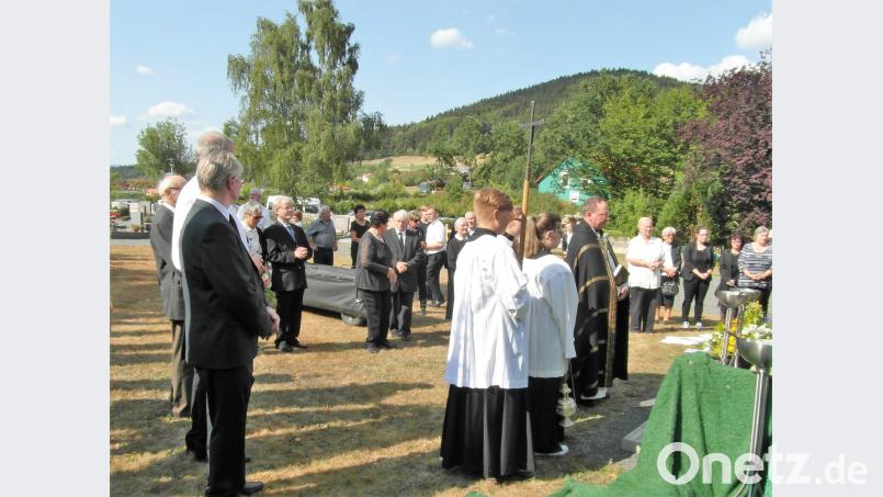 Pfarrer Heribert Stretz sowie die Angehörigen und Priester stehen am Grab. Bild: hl