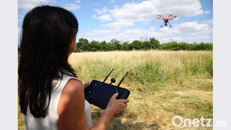 Tierschützerin Dagmar Seidenbecher steuert eine Drohne über ein Feld bei Gera. Sie soll dabei helfen, vor dem Mähen im Feld versteckte Rehkitze zu entdecken. Einsatzzwecke wie diesen befürworten viele Deutsche, doch sie machen sich auch Sorgen beim Thema Drohnen. Bild: Bodo Schackow/dpa