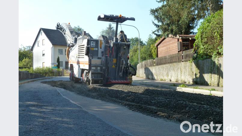 Die Asphaltfräse öffnete die Straße für die Arbeiten (links Kanal, rechts Wasserleitung). Damit die Autos trotzdem fahren können, drückte ein Bagger den Schotter wieder fest an. Bild: Portner