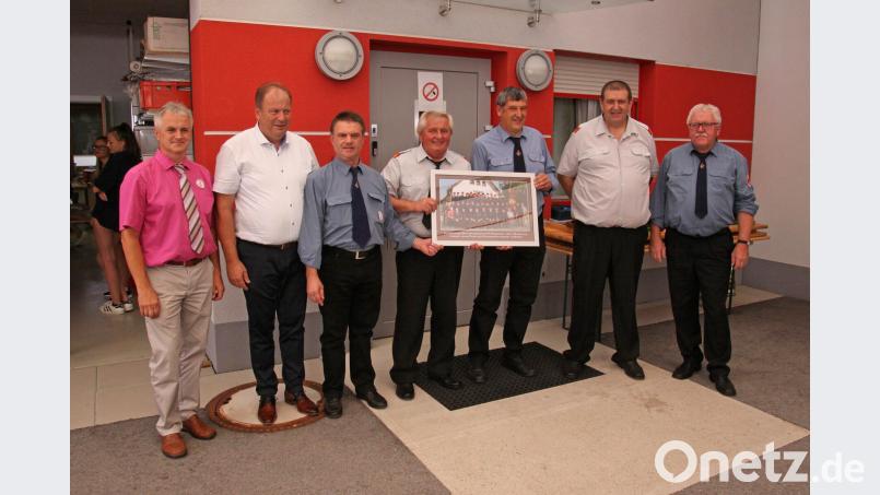 Als Festgeschenk zum 130-jährigen Bestandsfest überreichen Vorsitzender Gerhard Müller (Hausnummer 33, Dritter von links), Kommandant Gerhard Müller (Hausnummer 30, Dritter von rechts) und der frühere Vorsitzende Hermann Gmelch (rechts) den Mogersdorfer Kameraden ein Bild mit den Mitgliedern der Mockersdorfer Feuerwehr. Bild: ow