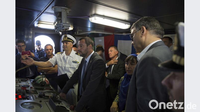 Matteo Salvini (Mitte), Innenminister von Italien, hört dem Kapitän eines Schiffes der italienischen Marine zu, der ihm auf der Brücke des Schiffes in der Marinebasis von Tripolis die Aufgaben erklärt. Bild: Mohamed Ben Khalifa/AP/dpa