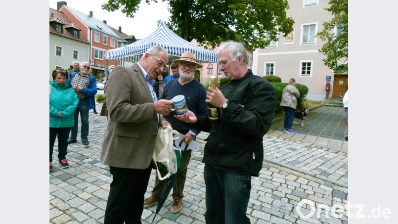 Klaus Lehl übergibt Willkommenspräsente (Sekt und Tasse) an KEM-Vorsitzenden Elmar Högl. Karlheinz Keck (Mitte) hieß die Oldtimer-Freunde willkommen. Bild: rn