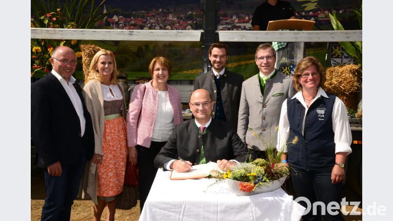 Beim Eintrag von Finanz- und Heimatminister Albert Füracker schauen stellvertretender Landrat Albert Nickl, Pleysteins Zweite Bürgermeisterin Andrea Lang, MdL Annette Karl, Landtagskandidat Stephan Oetzinger, Bürgermeister Hermann Ach und Erika Sauer, Vorsitzende des Fleischrinderverbandes Bayern über seine Schulter. Bild: bey