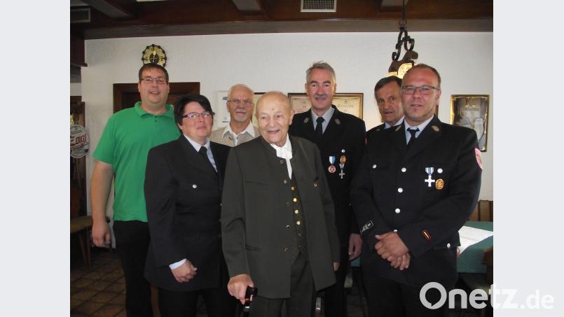 Hans Grabs (Mitte) ist das älteste Mitglied der Muglhofer Feuerwehr. Ihm gratulieren Vorsitzende Sieglinde Fleischmann, Kommandant Martin Graf (rechts), die Ehrenvorsitzenden Ernst Greiner (Zweiter von rechts) und Rudi Kreis (Dritter von rechts). Seinen Lebensabend verbringt der nun 95-Jährige auf dem Hof von Sohn Günther und Enkel Helmut (links hinten). Bild: ror