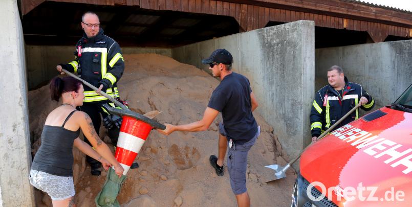 Die beiden Flosser Kommandanten Felix Müller (rechts) und Harald Träger (links) testen schon mal vorab das befüllen der Sandsäcke. Als Trichter wurde kurzerhand ein Leitkegel umfunktioniert. Neumitglied Svenja Lochner und Johannes Humig helfen bei den Vorbereitungen. Bild: mef