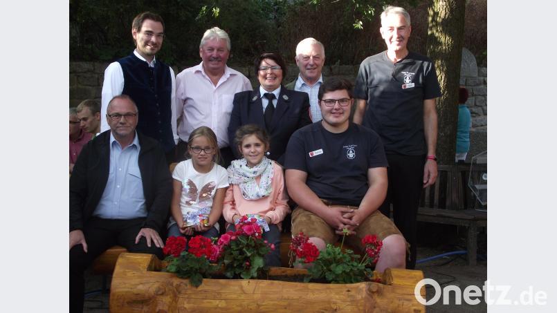 Die Hauptgewinner der Tombola. Alois Lukas (hinten, Zweiter von rechts), Auf der Bank Robert Ronke (links) und Thomas Fleischmann (rechts) mit den Glücksfeen Katharina und Lea. Es gratulieren Stephan Oetzinger und Hans Forster und die Feuerwehr Vorsitzende Sieglinde Fleischmann mit Ehrenvorsitzendem Rudi Kreis. Bild: ror