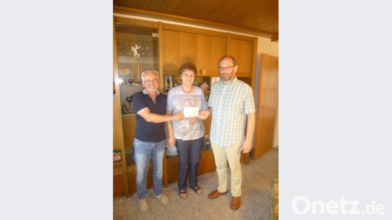 Pfarrgemeinderatssprecher Alfred Wulfänger überreicht an Brigitte Zetzll zusammen mit Pfarrgemeinderatsmitglied Roland Zötzl (von links) den Erlös aus dem Fastenessen für fünf Pakete nach Bogota Bild: fz